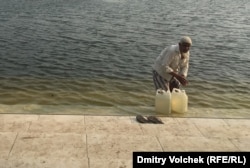 Паломник набирает святую воду из пруда возле мавзолея Хана Джахана Али