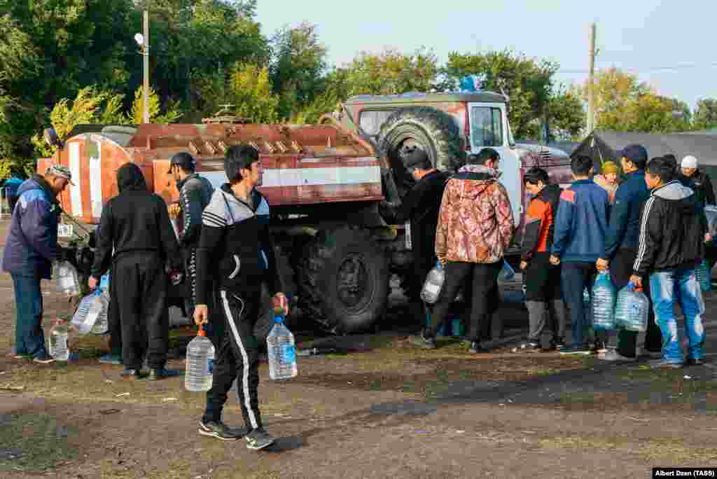 Люди набирают воду в пластиковые бутылки