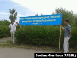 Өзіне тиесілі жер телімін «мемлекет қажетіне» алуға наразылық акциясында Қазақстан конституциясынан үзінді жазылған баннер ұстап тұрған адамдар. Астана, 28 наурыз 2014 жыл.