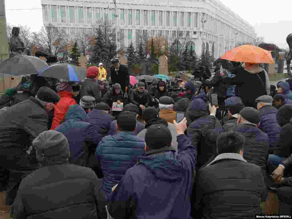 Тәуелсіздік ескерткіші алдында марқұм Дулат Ағаділге құран бағыштап отырған адамдар.