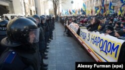 Шерушілер парламент ғимаратын күзеткен полиция жасағына қарсы "Парламент халықпен бірге" деген жазуы бар плакаттар алып шықты. Киеве, 3 желтоқсан 2013 жыл. 