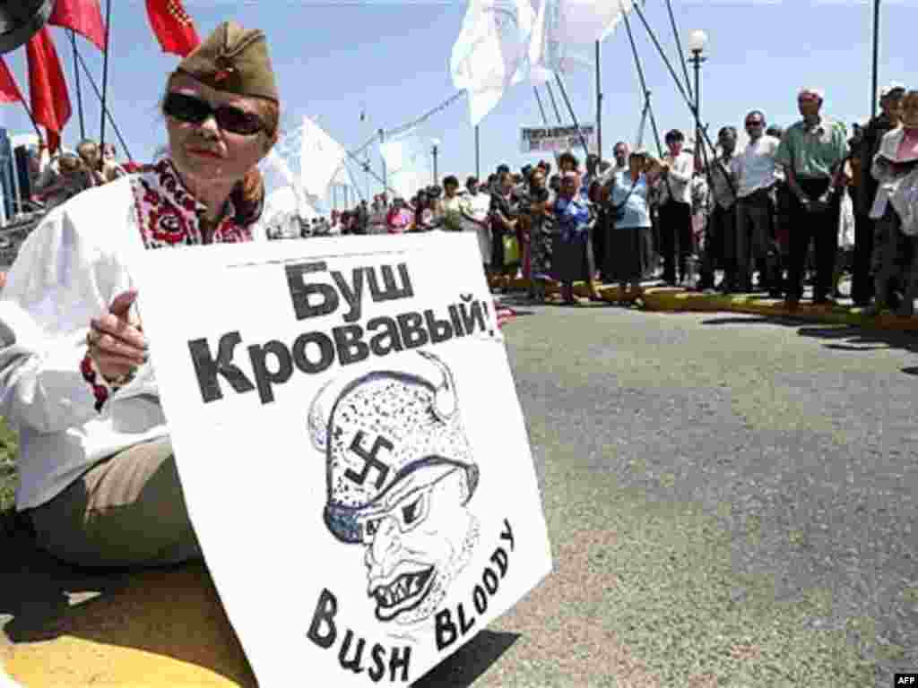 Ukraine -- A member of the Ukrainian Communist party, wearing a Soviet Army cap, holds a placard reading "Bush is bloody" during an anti-NATO protest at the port of Odesa, 09Jul2007