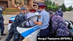 Полиция қызметкерлері суретші Асхат Ахмедияровты көлікке күшпен отырғызып жатыр. Нұр-Сұлтан, 13 шілде 2021 жыл.